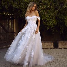 a woman in a white wedding dress standing on the ground with her hand on her hip