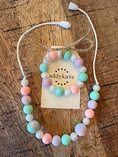 a necklace with pastel colored beads and a tag on the string that says, addy kate