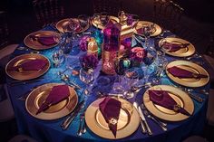 the table is set with purple and gold plates, silverware, and napkins