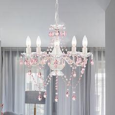 a white chandelier with pink beads hanging from it's center piece in a living room