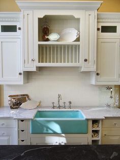 a kitchen with white cabinets and blue sink