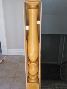 a tall wooden candle holder in a cardboard box