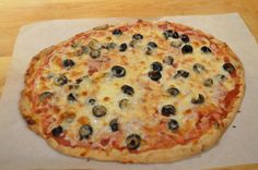 a pizza sitting on top of a piece of paper covered in cheese and olives