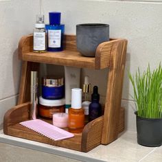 a wooden shelf with various items on it next to a potted plant