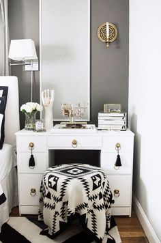 a white vanity with black and white accents in a bedroom area next to a bed