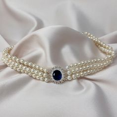 I took the inspiration for this pearl choker from Princess Diana's 18th birthday present from the Spencer's, this vintage sapphire necklace is a 3 strand faux pearl choker which will give you an exquisite layered necklace look. With a stunning sapphire stone set in a round bed of crystals taking centre of the choker.  This pearl choker necklace was beautifully handmade and will come in a organza bag inside a Lovett & Co pillow pack, perfect to give as a gift or to keep. We can offer a personalised message service for FREE, we will print it onto one of our beautiful vintage style postcards for you.  What would you like to say? 🤍Hypoallergenic  🤍Nickel Free Matching items available.  shorturl.at/mIJWY shorturl.at/ixPY2 Length: 30cm  With a 12cm adjuster chain. Width: 2cm Pearl Necklace With Brooch, Princess Diana Jewellery, Princess Necklace Jewellery, Princess Diana Pearl Necklace, Diana Jewellery, Diana Necklace, Princess Diana Jewelry, 18th Birthday Present, Sapphire Brooch