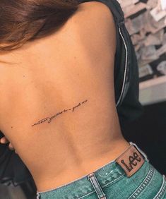 the back of a woman's lower back tattoo with words on her left side