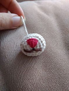 a hand holding a small crocheted object in the shape of a sheep