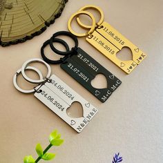 three different types of personalized metal key chains on a table next to a flower