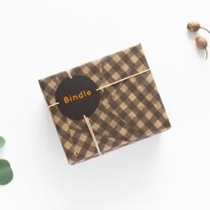 a brown and white checkered wrapping paper with the word binde on it next to some green leaves