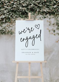 a sign that says we're engaged on it next to a wall covered in greenery