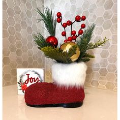 a christmas stocking with red berries and greenery sits on a counter next to a box of joy