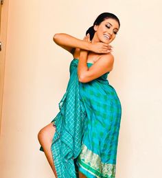 a woman in a blue dress posing for the camera with her arms around her neck