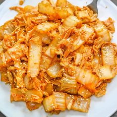 a white plate topped with meat and onions on top of a wooden table next to a fork