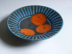 an orange and blue bowl with two bears on the inside sits on a white surface