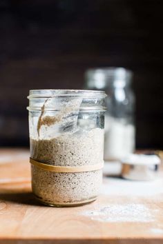 a jar filled with sand sitting on top of a wooden table next to two salt shakers