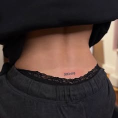 a woman with a small tattoo on her lower back and the word love is written in black ink