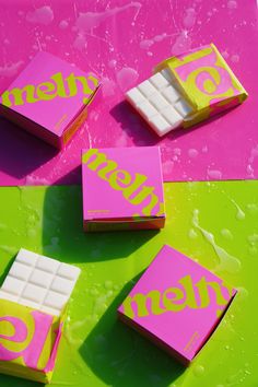 some pink and yellow pieces of candy sitting on top of a green table with drops of water