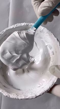 a person is using a toothbrush to brush the white icing on a bowl