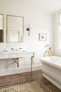 a bathroom with two sinks and a bathtub in the corner, along with mirrors on the wall