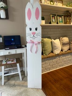 a cardboard bunny sitting on top of a wooden floor next to a white table and chair