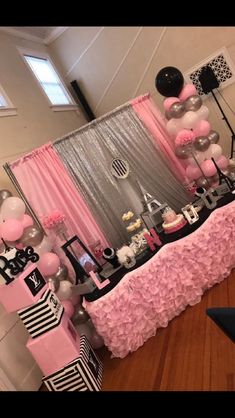 a table topped with balloons and cake next to a wall covered in pink ruffles