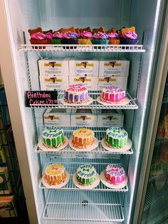 a refrigerator filled with cakes and cupcakes on top of it's shelves