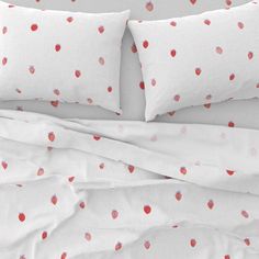 an unmade bed with white sheets and strawberry print