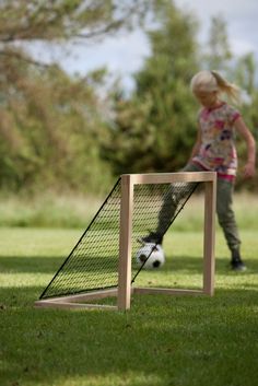 a small child playing with a soccer ball in the grass next to a goal post