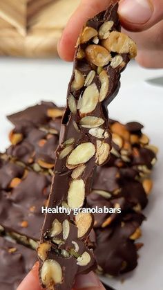 a person holding a chocolate bar with nuts on top