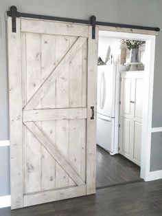 a white refrigerator freezer sitting inside of a kitchen next to an open barn door