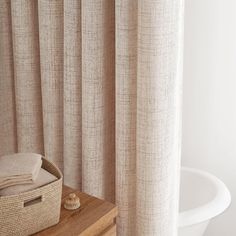 a basket sitting on top of a wooden table next to a curtain