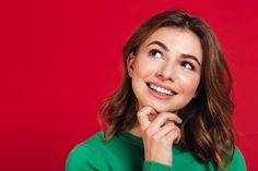 a woman in a green shirt is smiling and looking at the camera with her hand on her chin