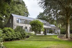 the house is surrounded by lush green trees and grass, with stairs leading up to it