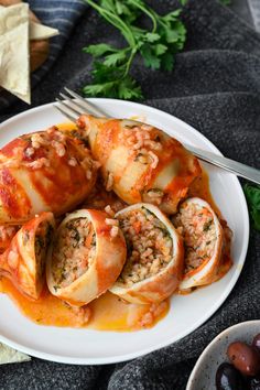 a white plate topped with stuffed shells covered in sauce and garnished with parsley