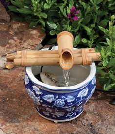 a blue and white planter with a bamboo spout in it's center