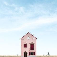 a pink house sitting on top of a wooden fence