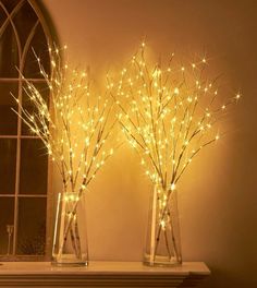 two vases filled with lights sitting on top of a mantle