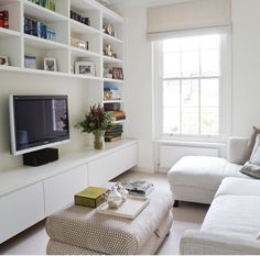 a living room filled with furniture and a flat screen tv sitting on top of a white book shelf