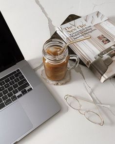 an open laptop computer sitting on top of a white desk next to a cup of coffee