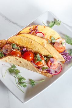 a white plate topped with two tacos covered in veggies