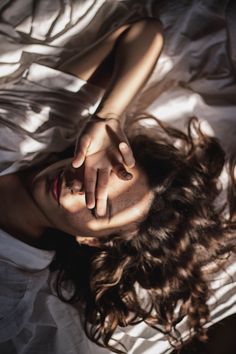 a woman laying on top of a bed with her hands resting on her head and eyes closed