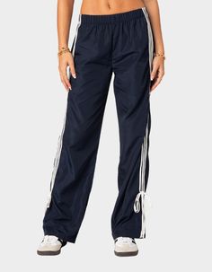 These Track Pants Offer Both Style And Comfort, Making Them Perfect For A Sporty Yet Fashionable Look. They're Ideal For Any Activity, Ensuring You Feel Comfortable And Confident Throughout Your Entire Day. Track Pants. Side Stripe Detailing. Ribbon Tie Ankle Detail. Elastic Waist. 100% Polyester. Item Care: Wash With Similar Colors. Model Wears Size S. Model Height Is 5'8. | Edikted Remy Ribbon Track Pants 80s Y2k, Pants Jogger, Track Pants Women, Wide Leg Sweatpants, Pants Details, Low Rise Jeans, Leather Mini Skirts, Jogger Sweatpants, Knit Pants