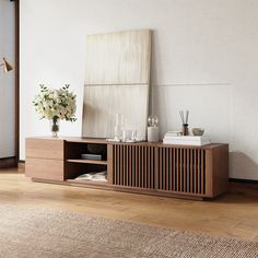 a wooden cabinet with candles and flowers on top in a room that has hardwood floors