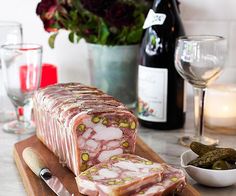 a large piece of meat sitting on top of a cutting board next to a bowl of pickles