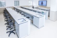 an empty office with chairs and desks in front of a flat screen tv on the wall