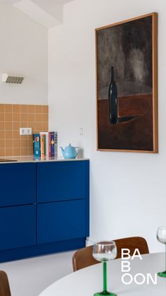 a kitchen with blue cabinets and a painting on the wall