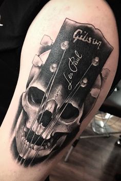 a black and white photo of a guitar with skulls on it's arm,