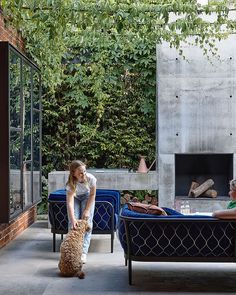 two people sitting on chairs with a dog in front of them and a fire place behind them