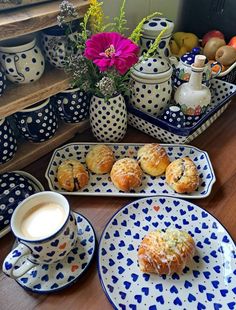 blue and white plates with pastries on them next to a vase filled with flowers